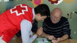 Voluntario de Cruz Roja enseñando funcionamiento de smartphone a persona mayor