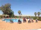 Grupo de usuarios en cadeira de rodas rodeando unha piscina