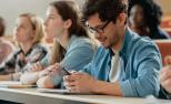 Un mozo utiliza o seu smartphone nunha clase na universidade.