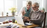 Una pareja de personas mayores utiliza Internet con un ordenador portátil.