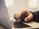 Man tecleando sobre un portátil.