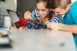 Una chica y un chico construyendo un robot.