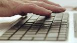 Man de persoa maior sobre un teclado.