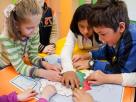 Niños jugando con un plano en relieve Braille.