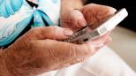 Manos de mujer mayor sosteniendo un smartphone.