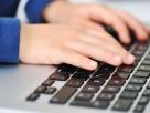 Manos de niño sobre el teclado de un portátil.