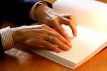 Mans lendo libro en Braille.