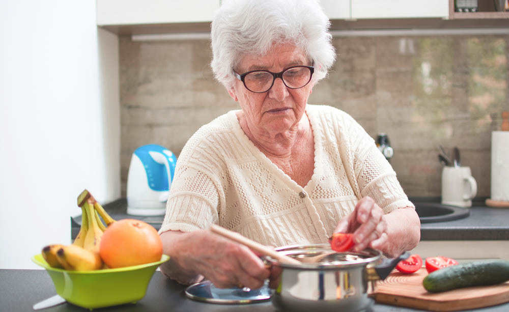 Fotografía dunha muller maior cociñando.